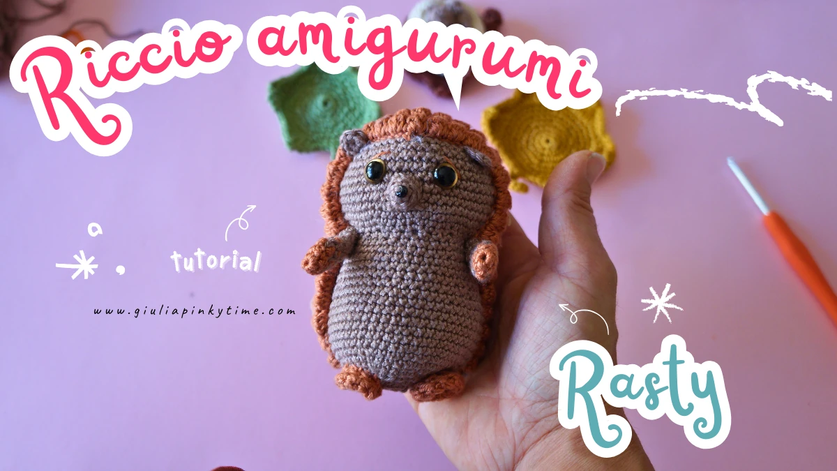 Come realizzare un dolce riccio amigurumi: Tutorial passo-passo 4 Riccio amigurumi marrone con musetto chiaro, appoggiato sulla mano di Giulia, sfondo rosa con decorazioni autunnali all’uncinetto: foglie palmate, zucca beige e uncinetto arancione. Scritta “Riccio Amigurumi - Rasty.