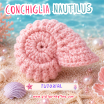 Conchiglia Nautilus all'uncinetto rosa realizzata a mano e appoggiata sulla sabbia in uno scenario marino decorato con coralli, stelle marine, conchiglie e perle nei colori pastello della collezione Pinky Summer Time.